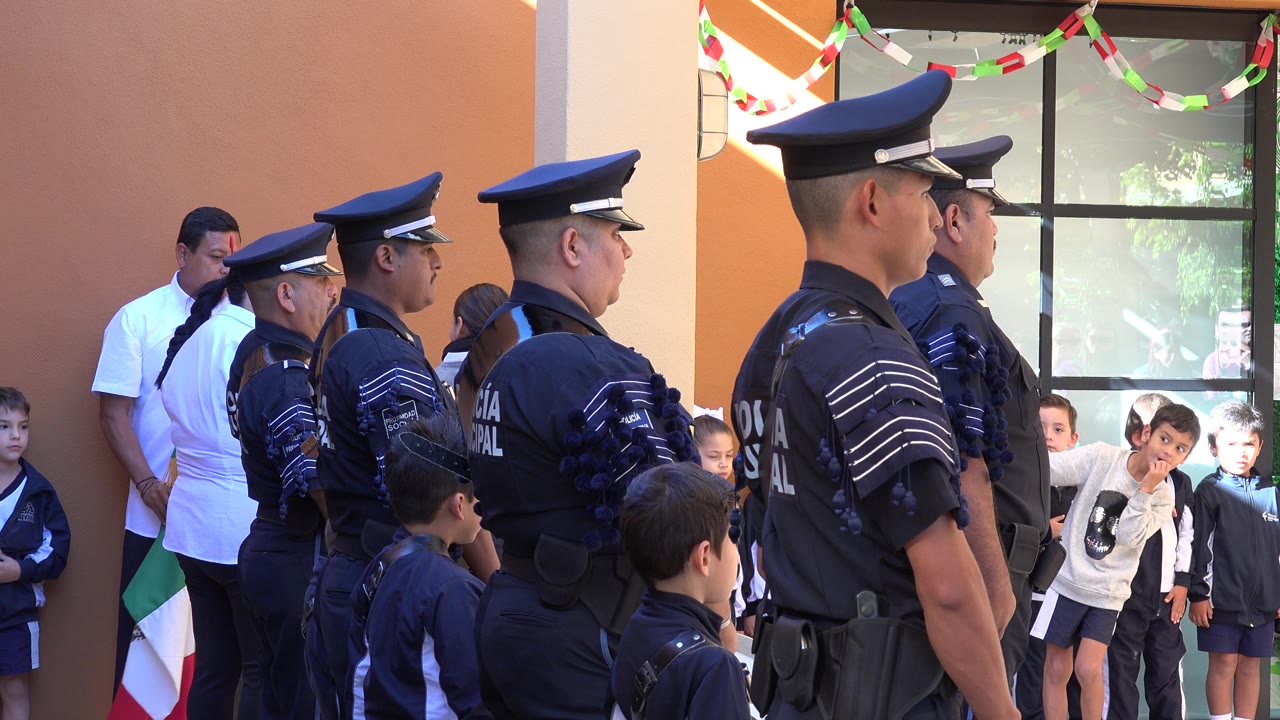 Children lean and look toward police officers standing outside the school.
