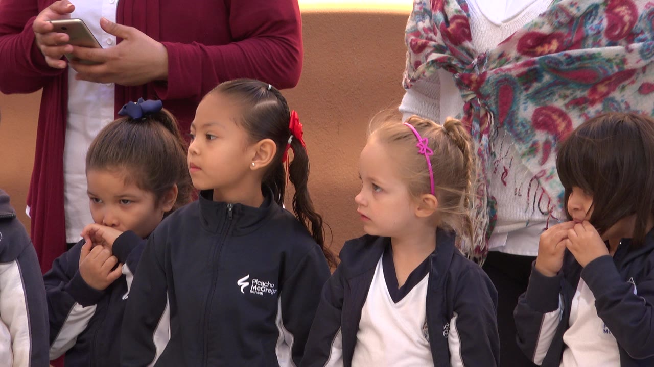 Young girls standing in line with adults behind them.