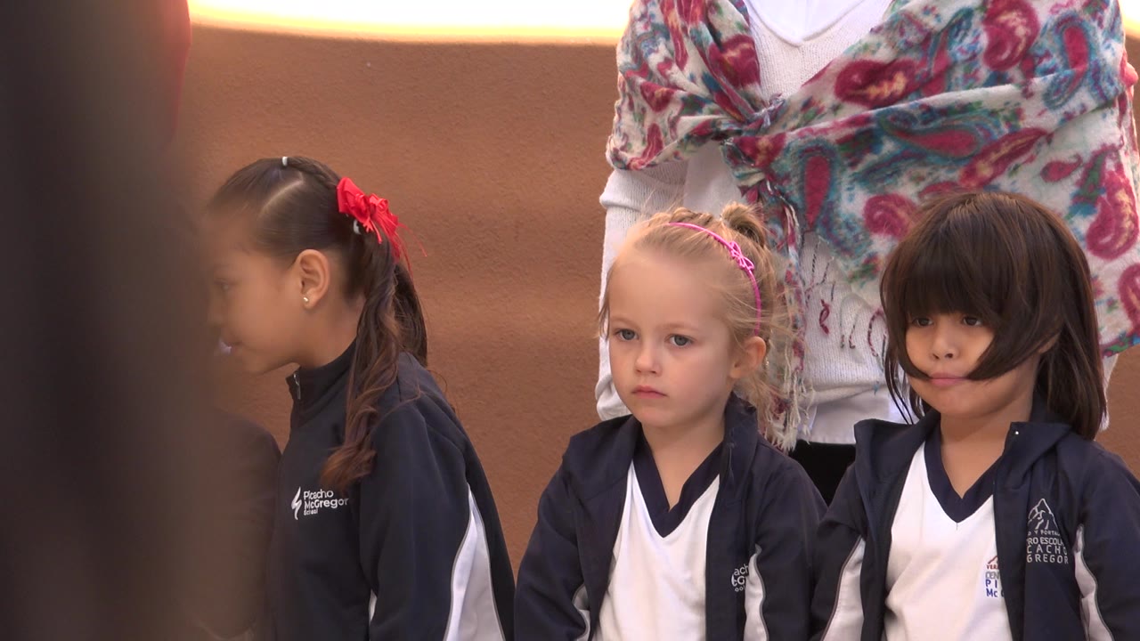 Children in matching navy and white outfits standing with adults behind them.
