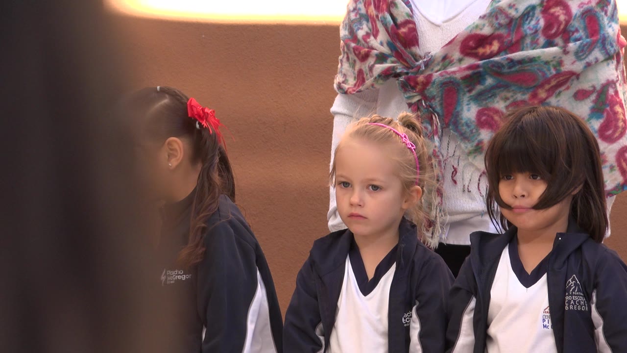 Three children in coordinated navy and white outfits stand under warm indoor light in San Jose del Cabo, Mexico, with an adult's patterned scarf visible behind them.