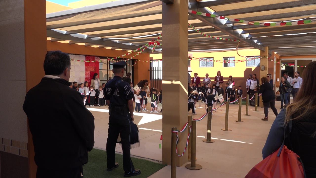 Adults watch children seated in a decorated courtyard.