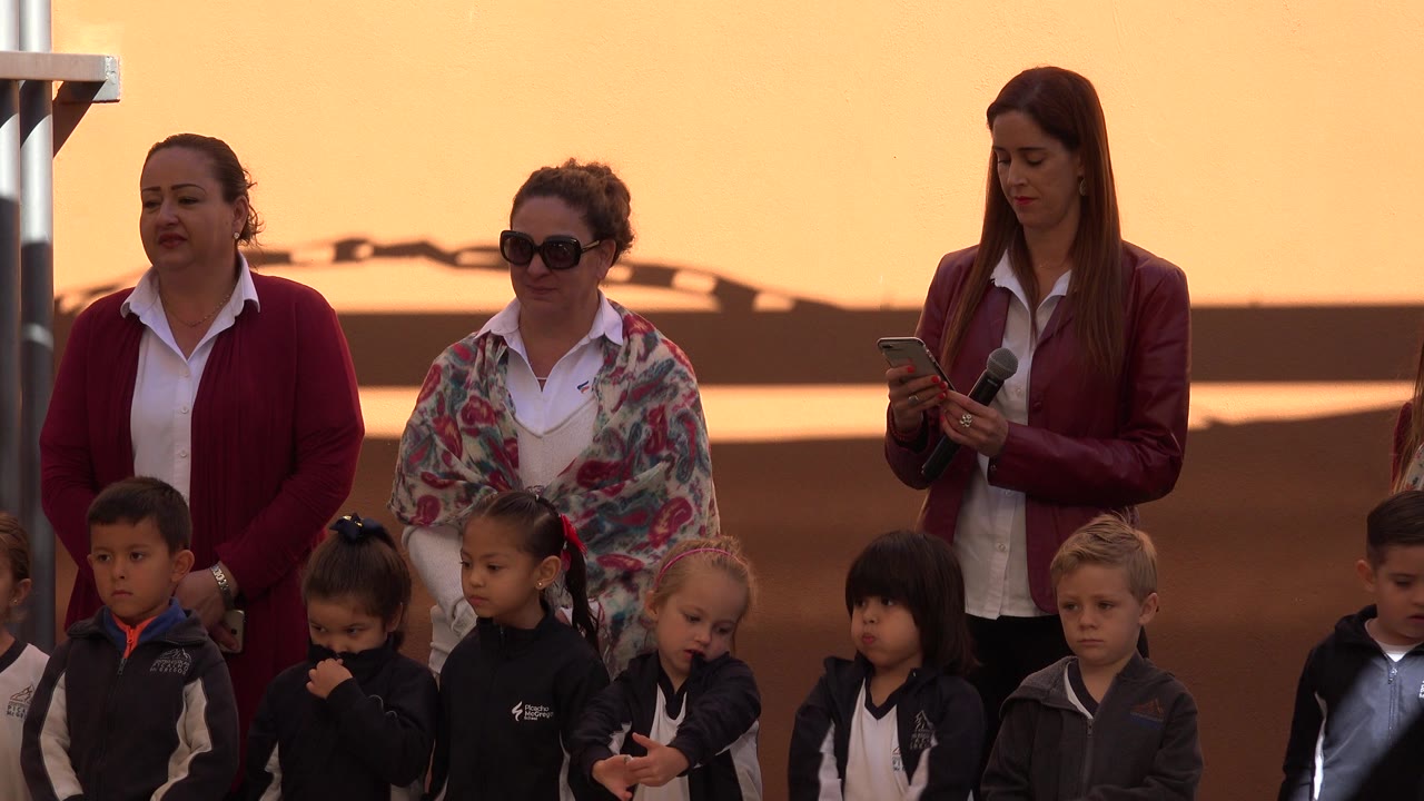 Children in soccer uniforms stand in front of three adult women at an awards ceremony.