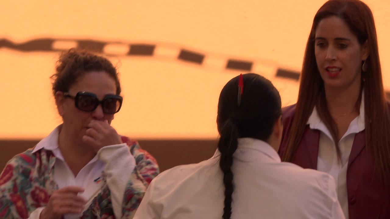 Two adult women and a child seen from behind in warm outdoor light.