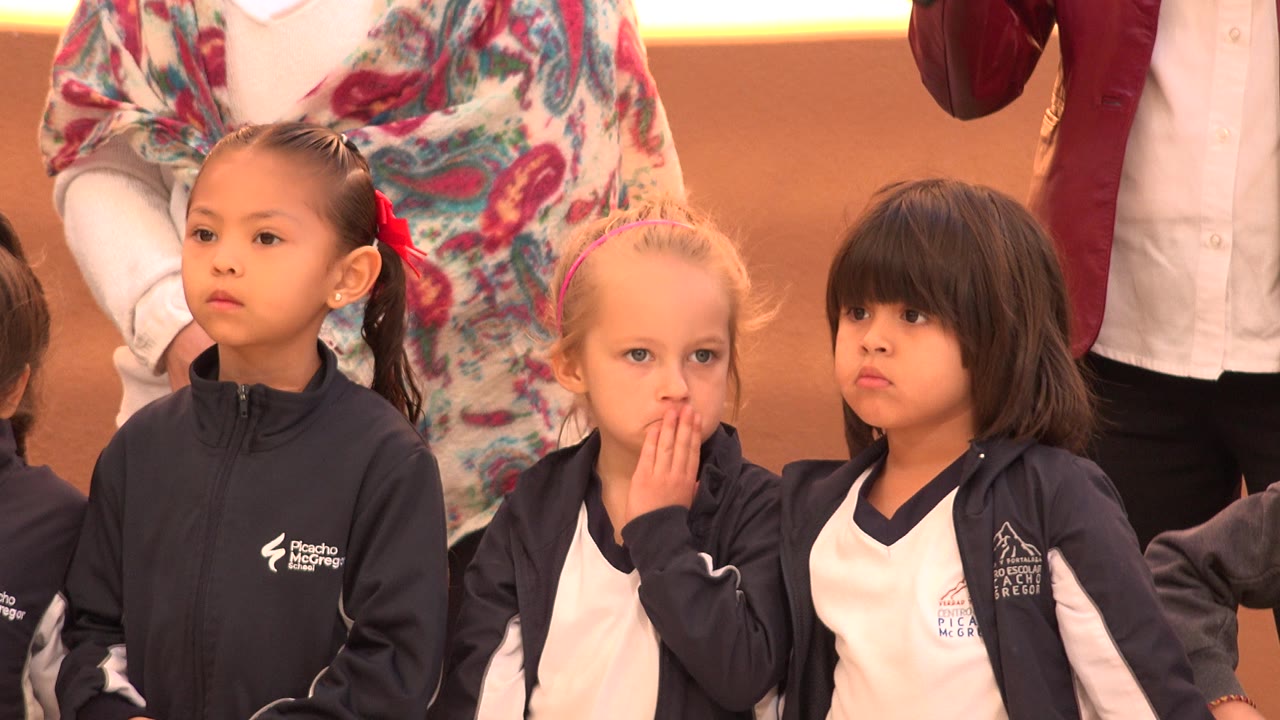 The blond-haired girl holds her fingers to her mouth while standing between two young girls in sportswear at the San Jose Del Cabo youth sporting event.