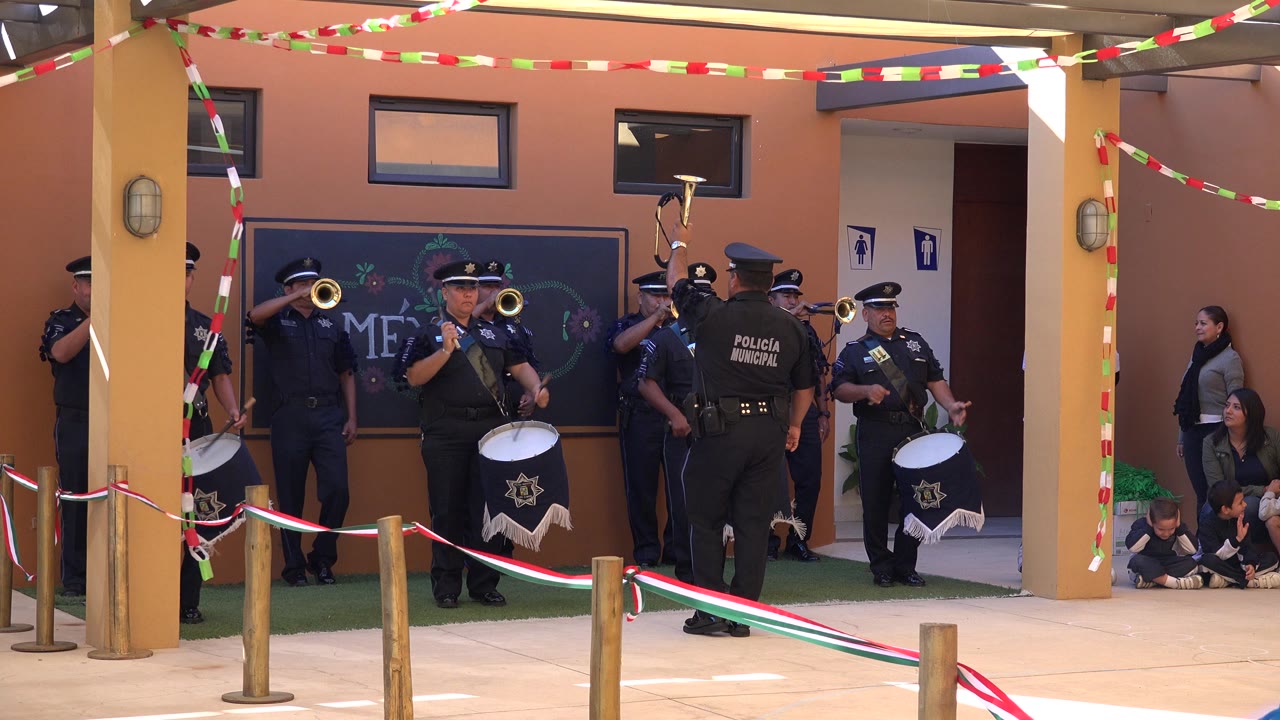Uniformed musicians play drums and trumpets at a decorated public event.