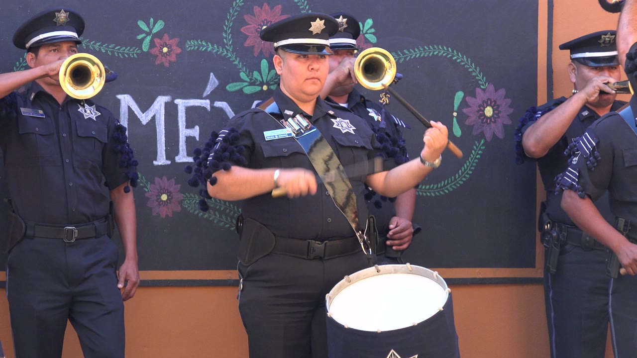 Centered drummer plays while trumpet players stand close behind.