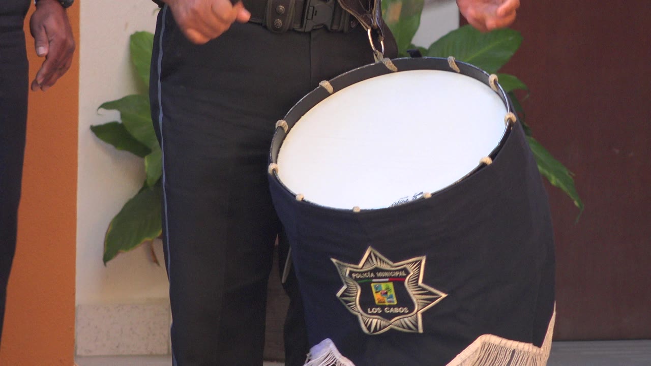 At 0:01, the San Jose del Cabo performance remains tightly framed on the drum, with the performer's hand hanging beside the strap and the emblem centered on the drum cover.