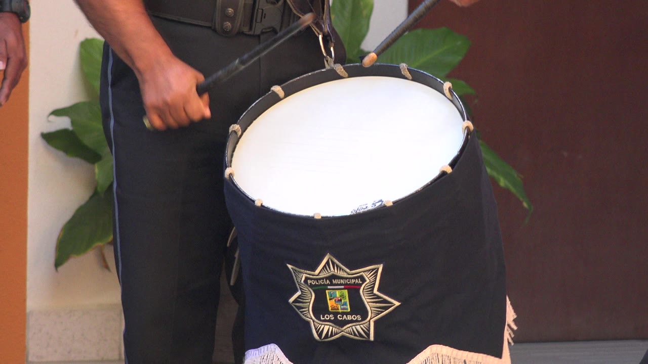 At 0:00, a uniformed person in San Jose Del Cabo, Mexico holds drumsticks over a large black drum with a municipal-style star patch visible on the cover.