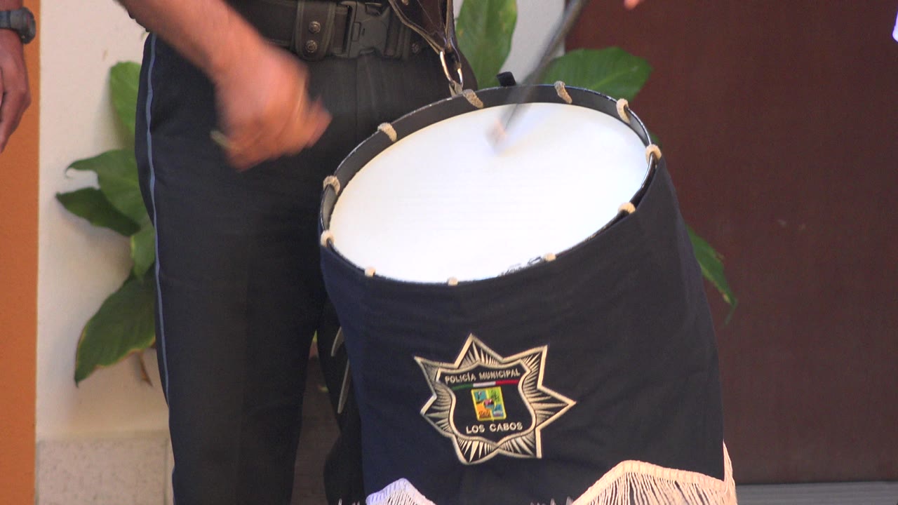 Blurred drumstick motion above a white drumhead and black drum cover.