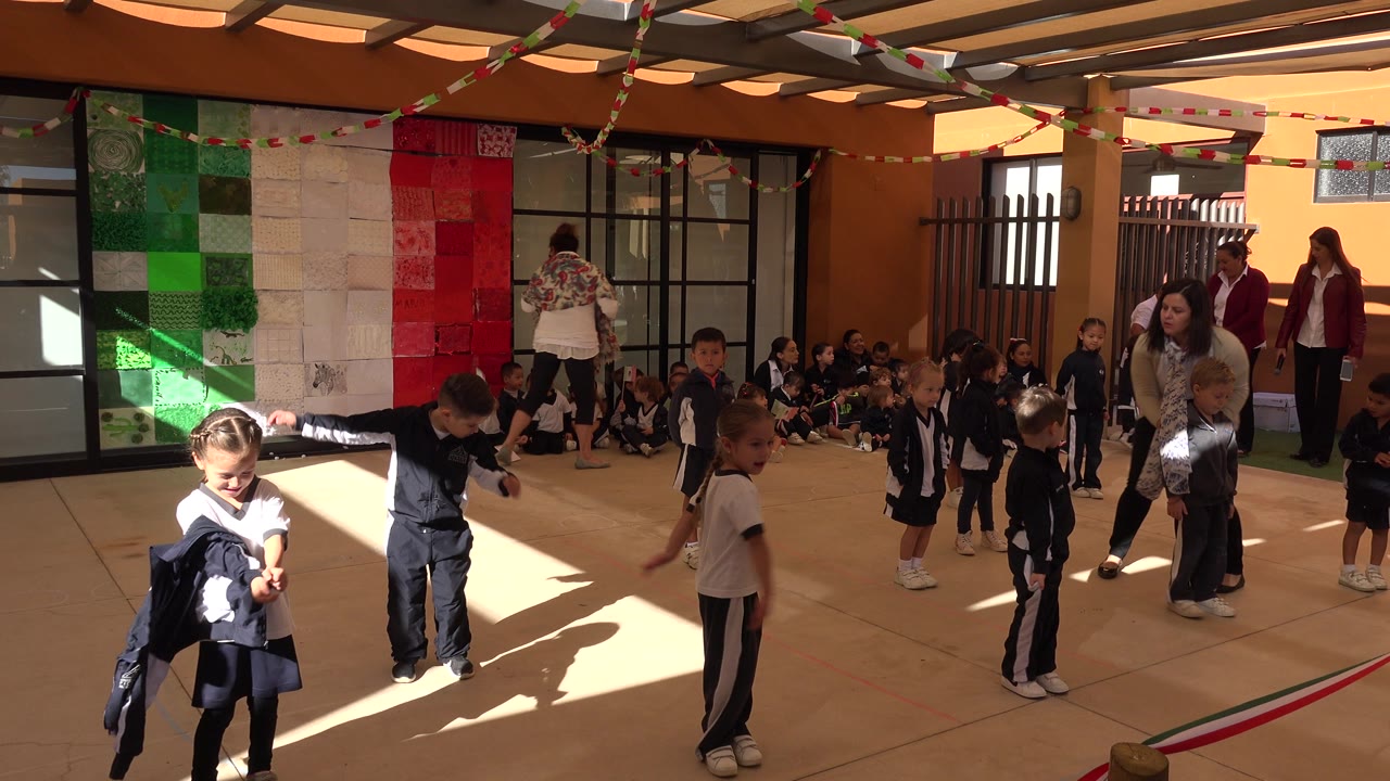 At 0:01 in San Jose del Cabo, Mexico, children in matching athletic clothes shift positions during warmups while a group of classmates remains seated near the back wall.