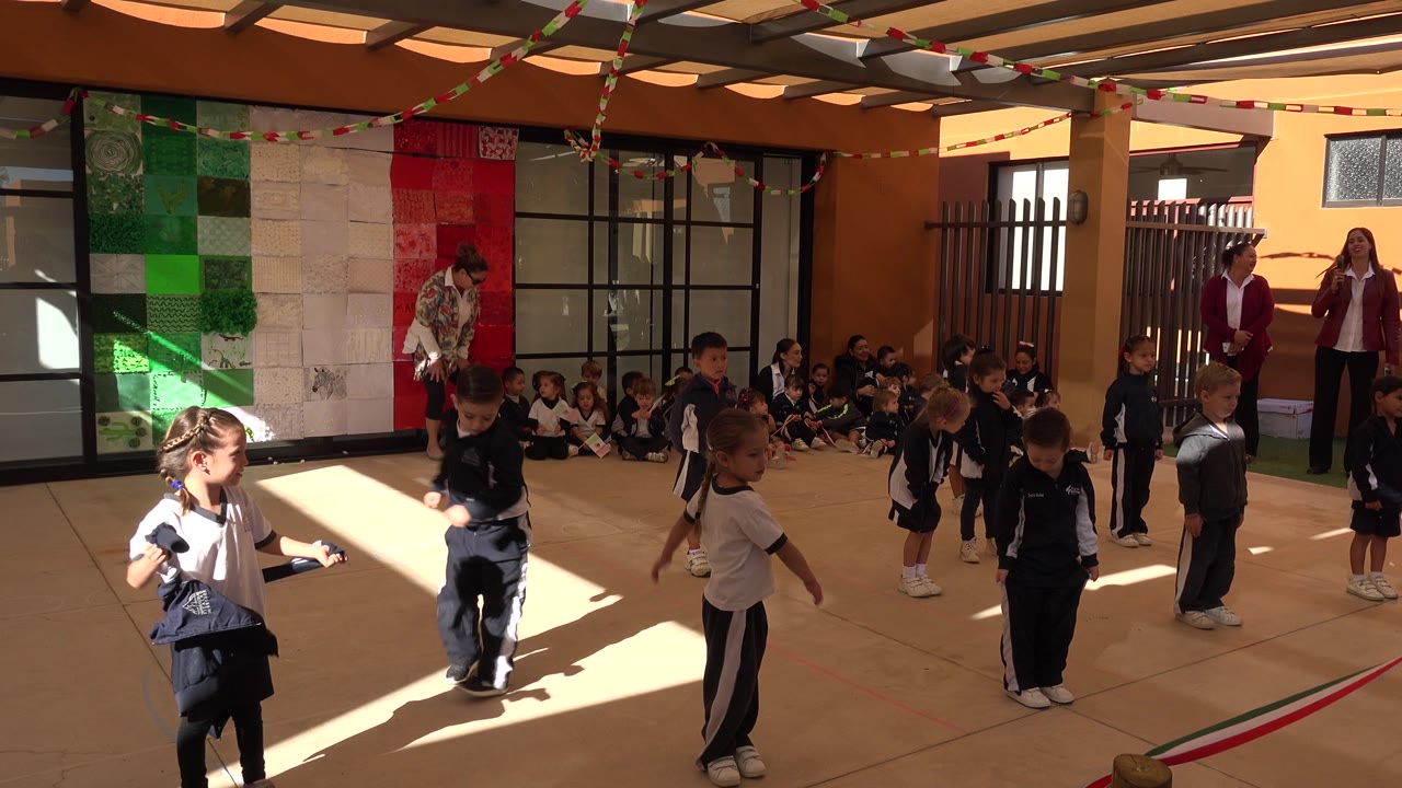 Children in school uniforms line up in a decorated courtyard.