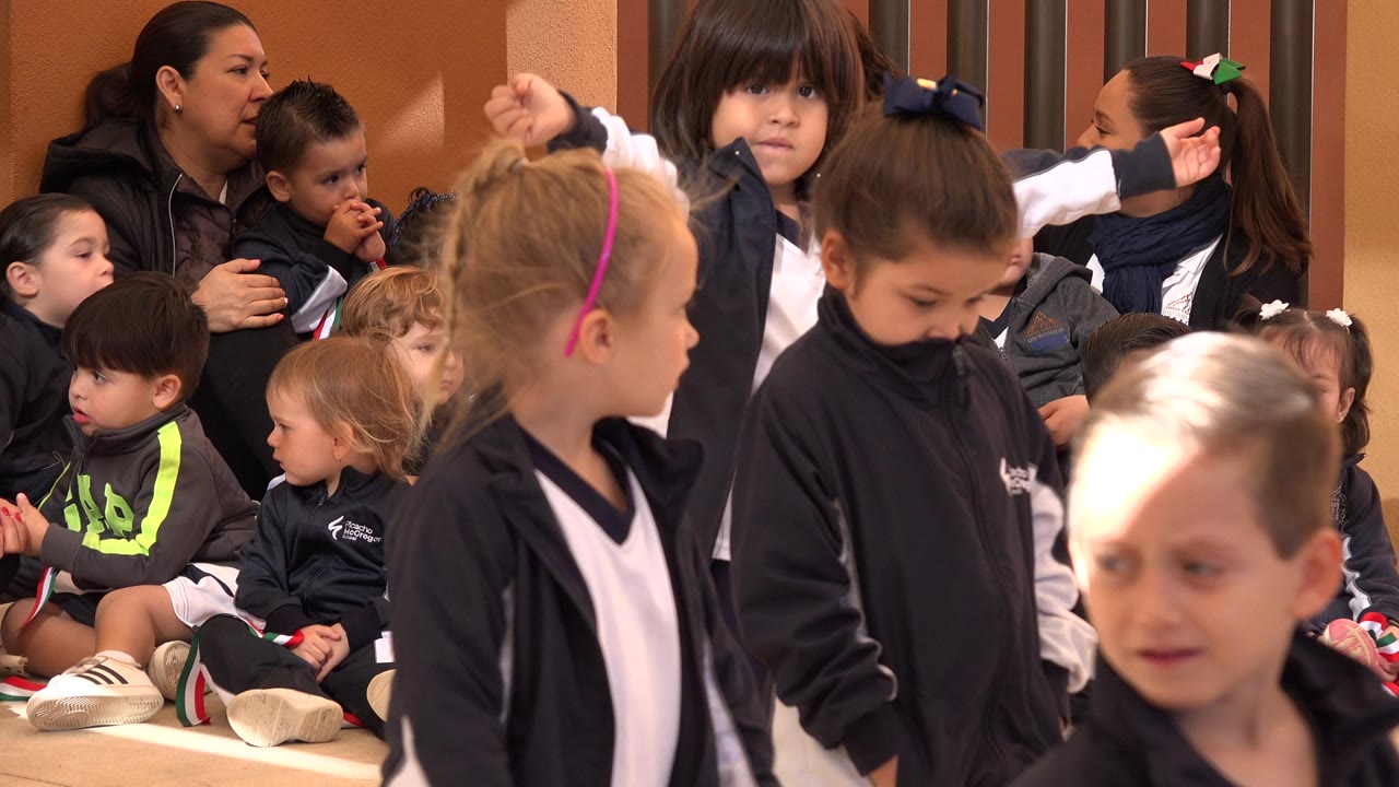 Children in athletic uniforms waiting with adults seated behind them.