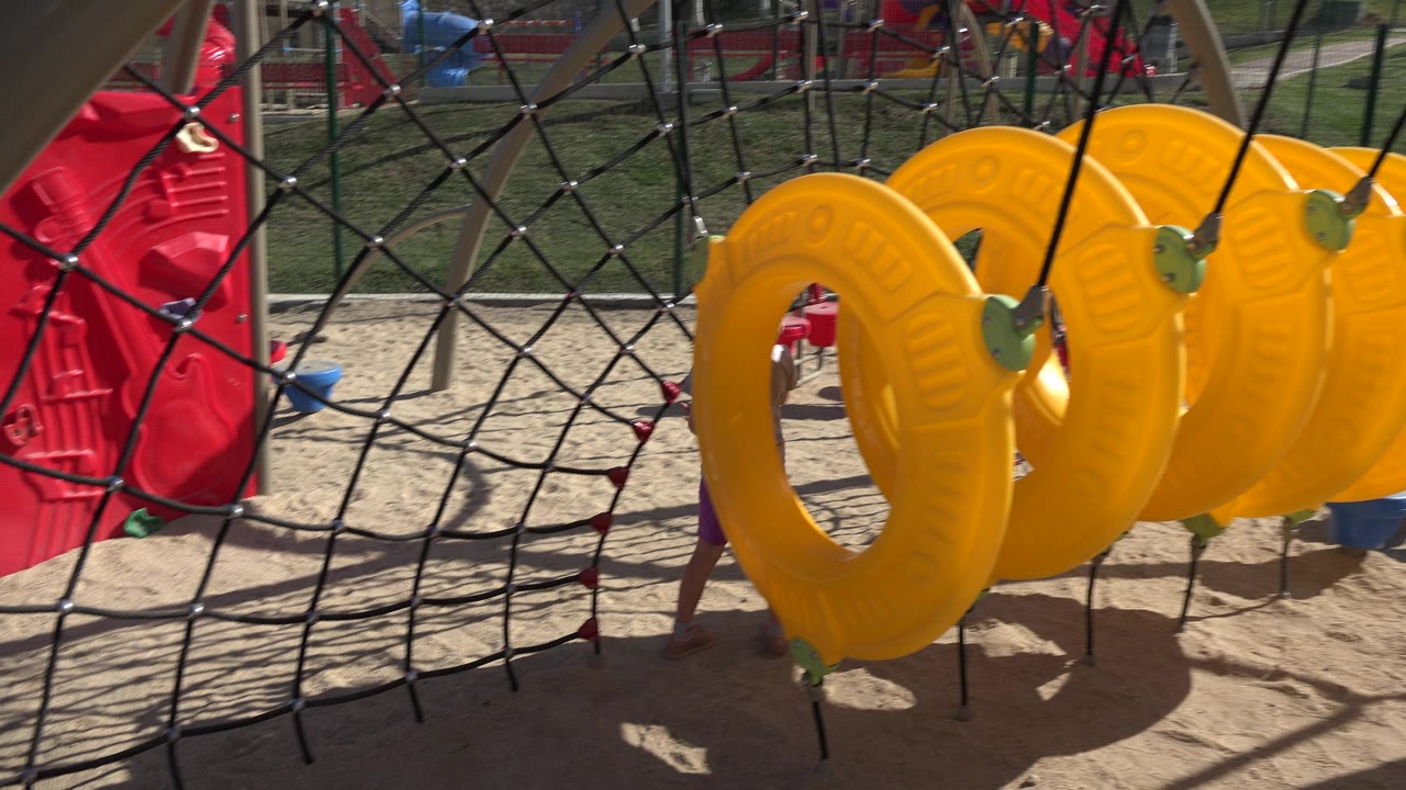 Yellow playground rings and rope net over sand.