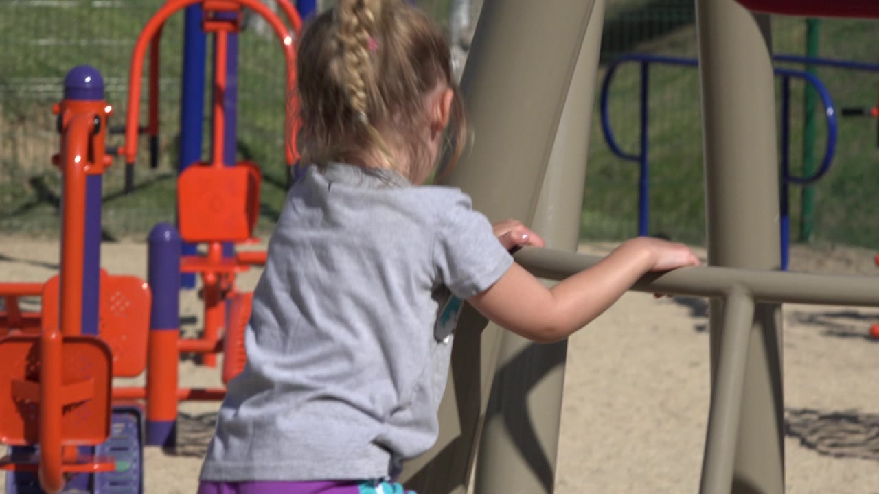 Child from behind near playground climbing structure.