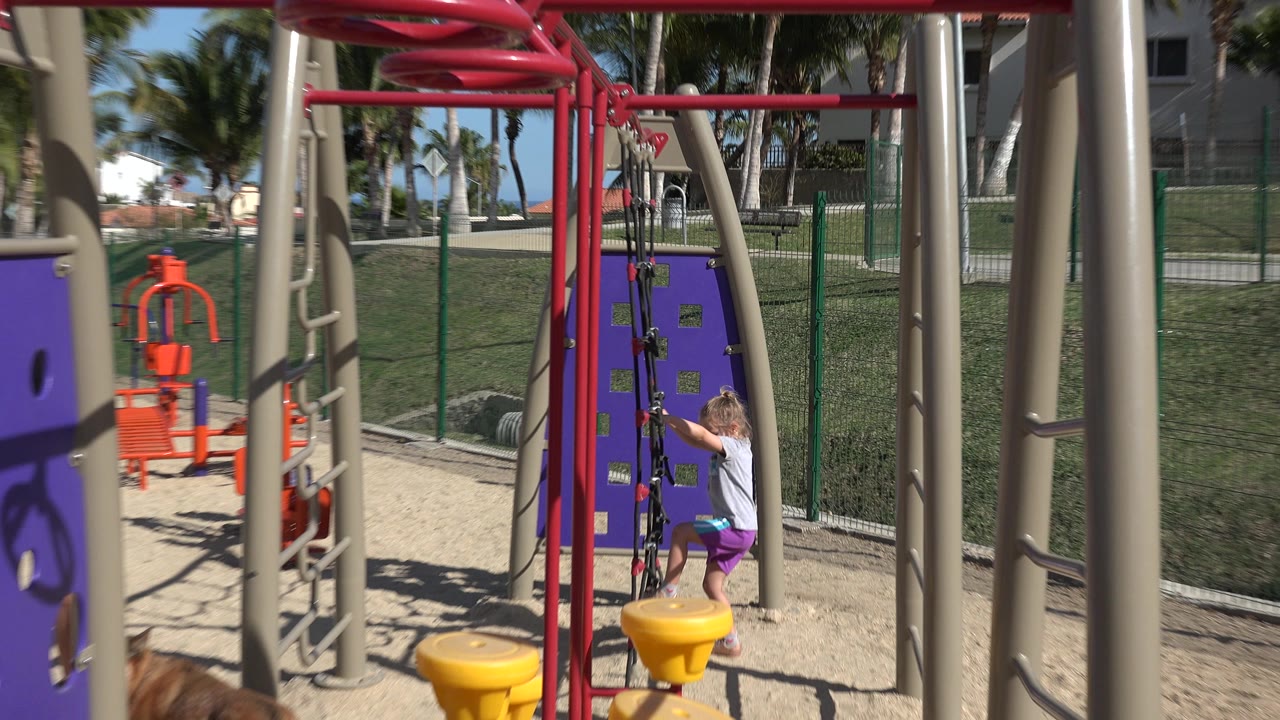 Young girl climbing a rope net on a playground structure.