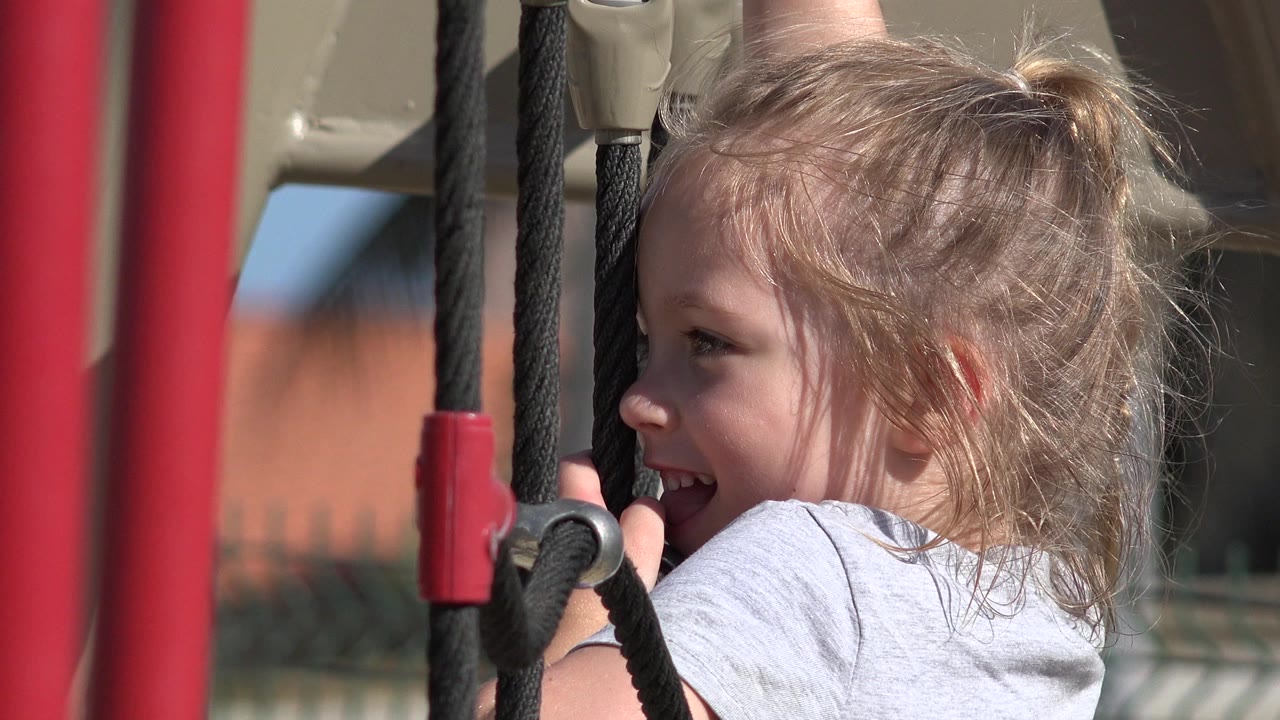 Young girl smiling beside playground ropes