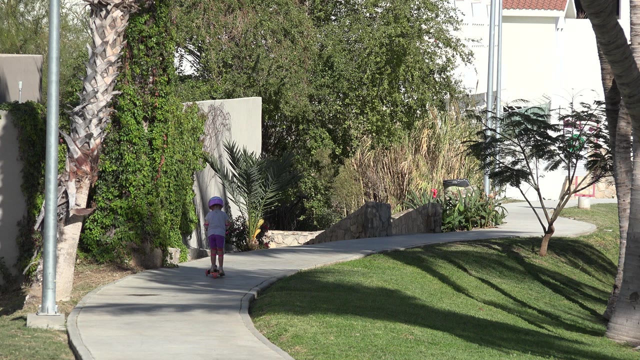 Child on a scooter at the start of a curved sidewalk.