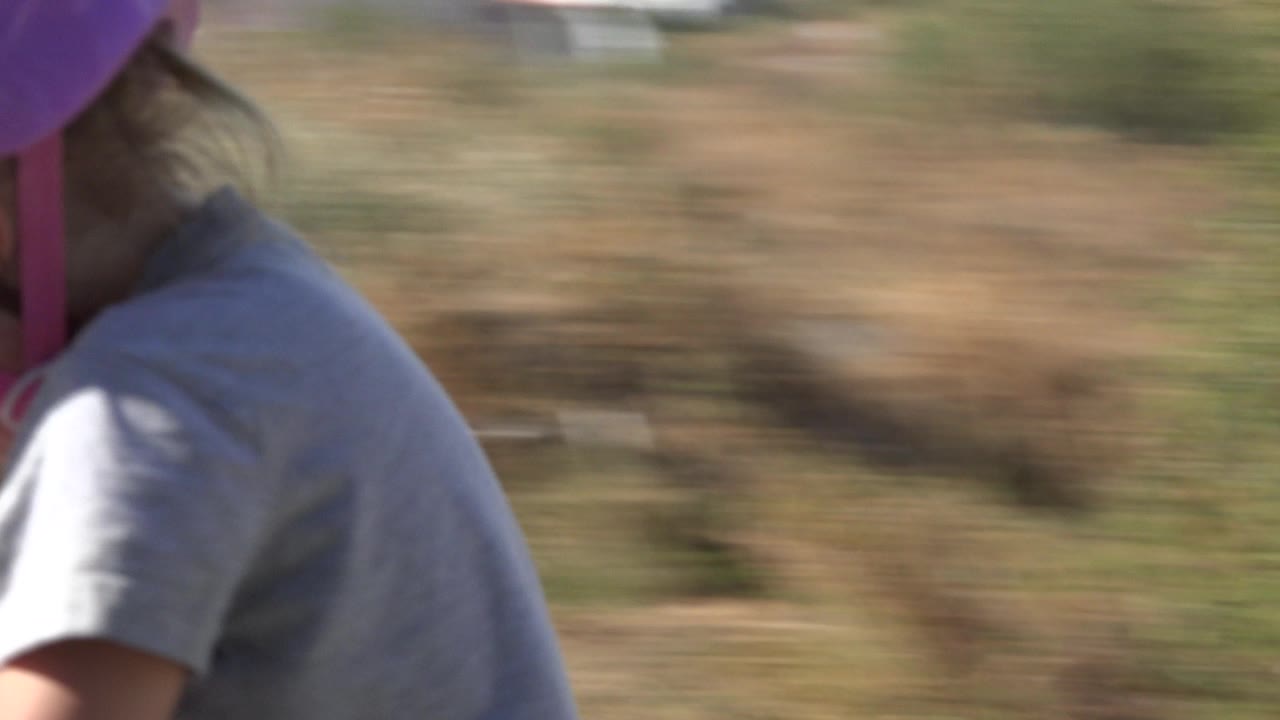 Close side view of a helmeted child riding a scooter.