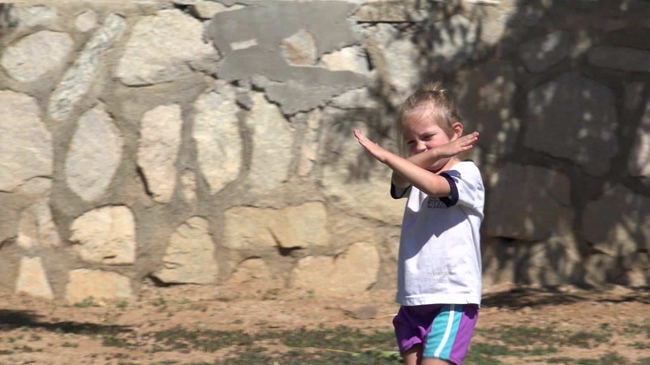 Blonde girl crossing her arms in front of a stone wall.