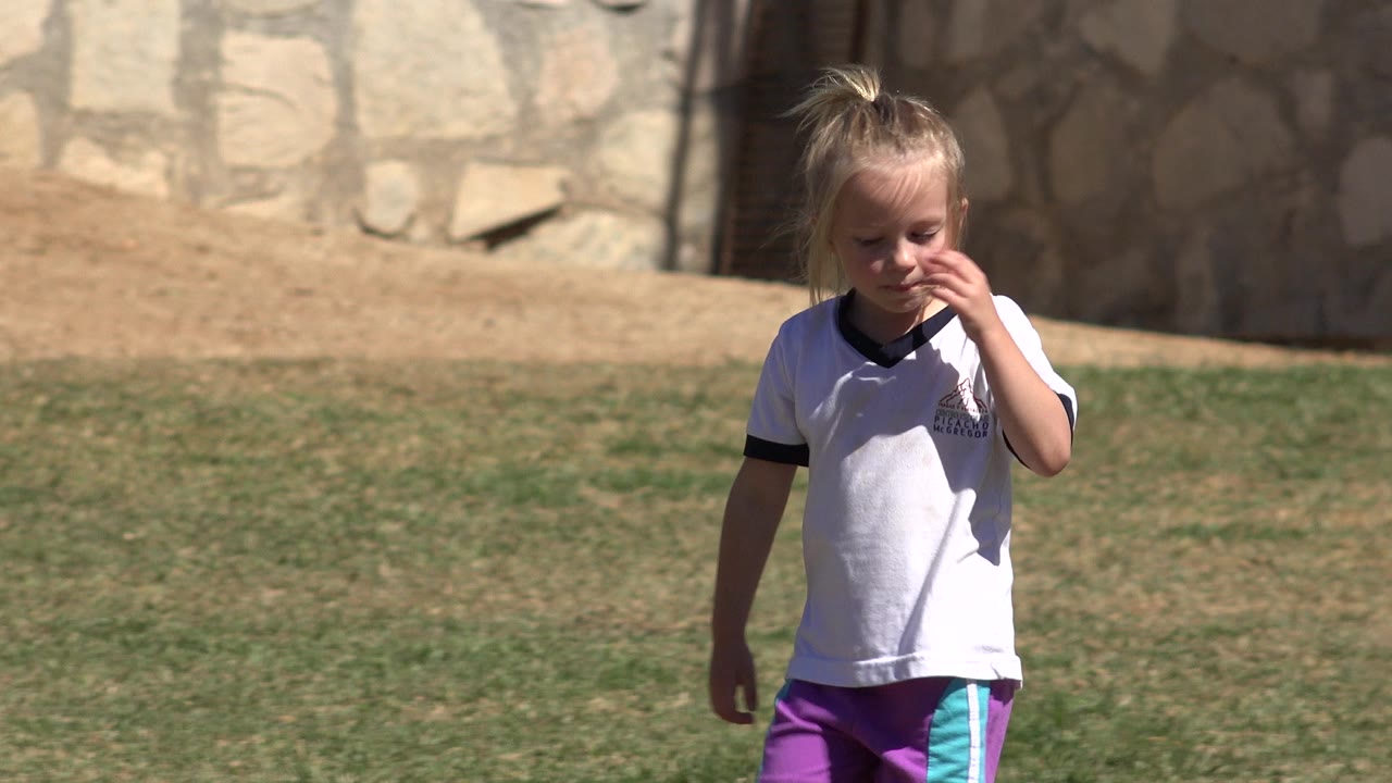Young girl walking on a sunny grass field.