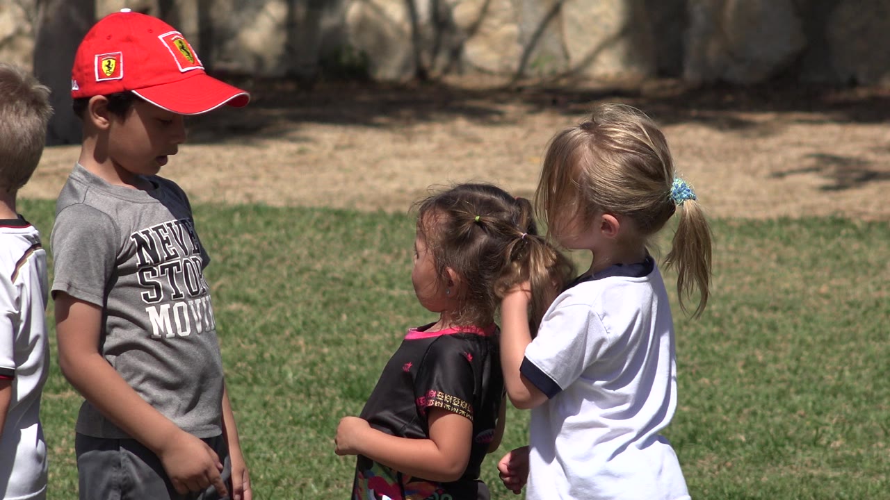 The boy in the red baseball cap stands at left while two girls face him on the grass in San Jose Del Cabo, Mexico.