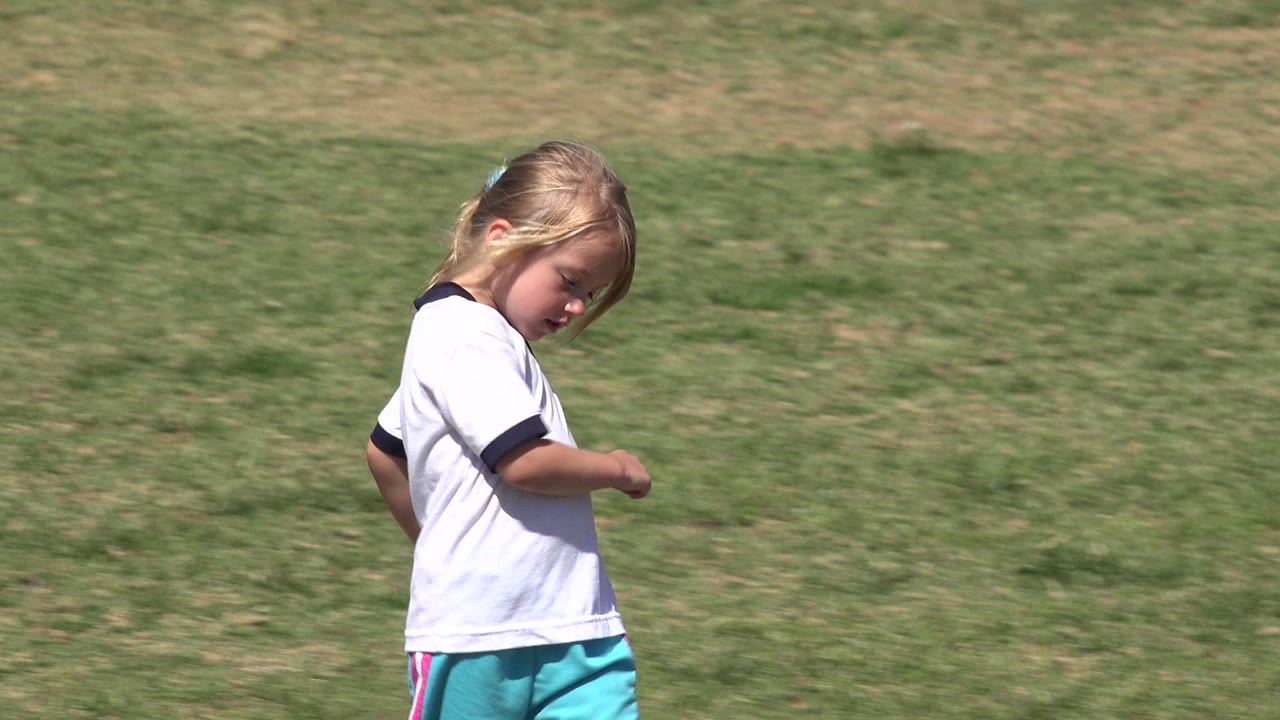 Young girl turns while running on the grass field.