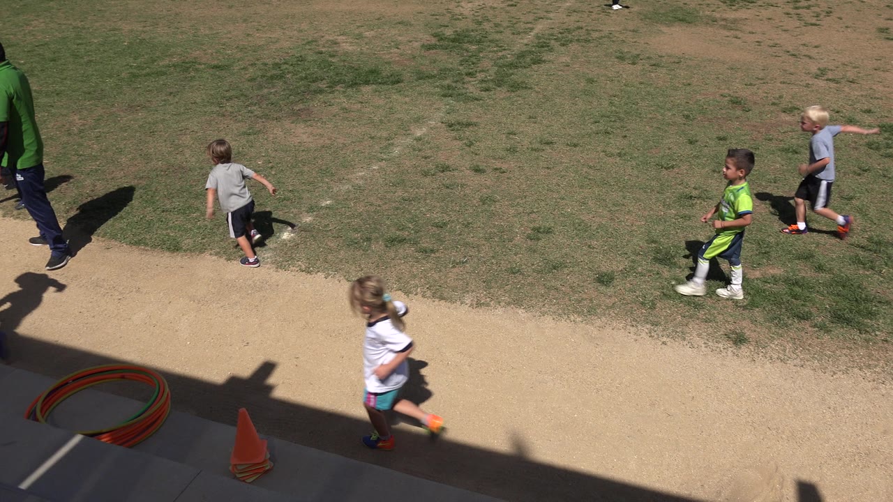 Children running beside a grass field from an elevated view.