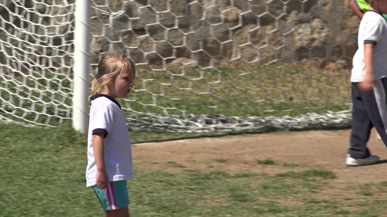 The girl remains near the goal mouth while another child in a white shirt passes behind the net area in San Jose del Cabo, Mexico.
