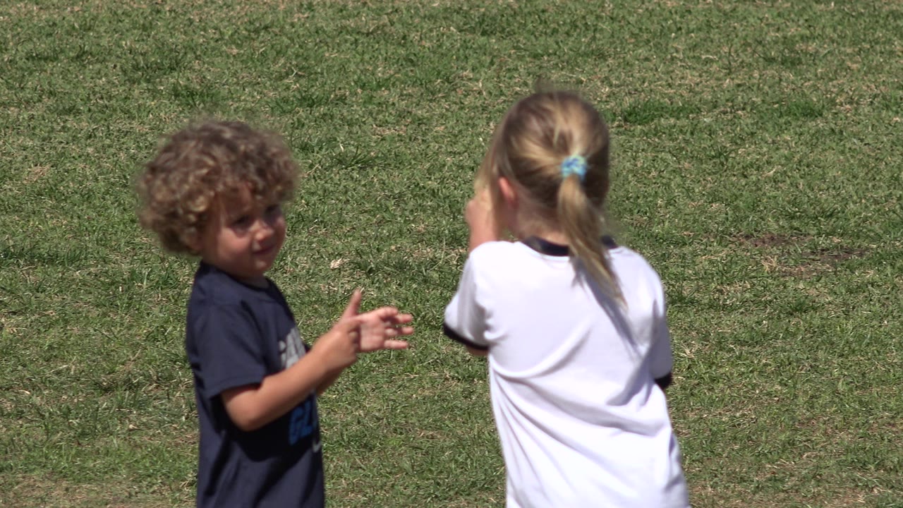 Two children standing on a green lawn.