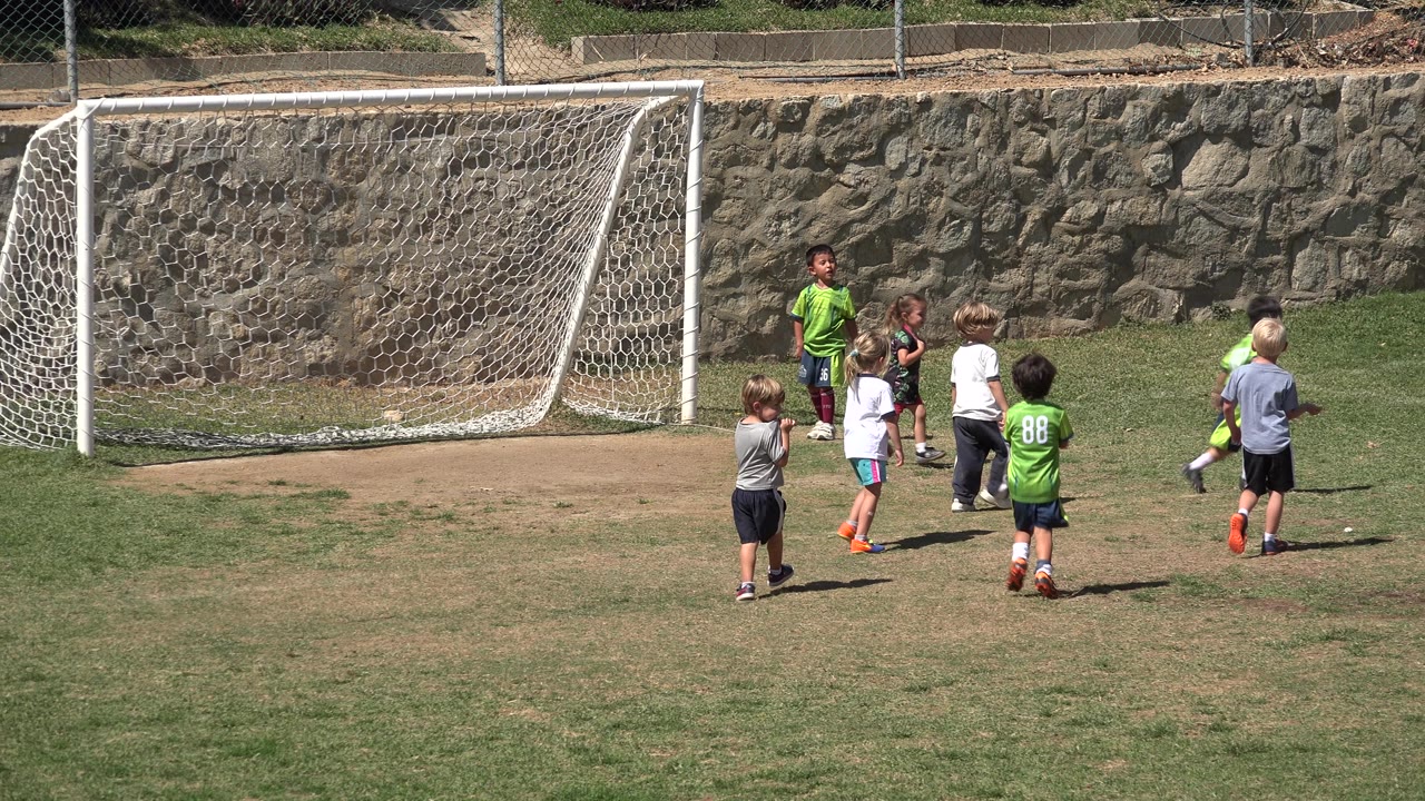 Children walk away from the soccer goal across the field.