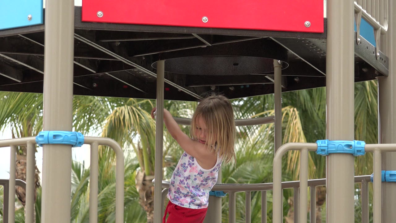 The young girl remains framed between tan posts as she reaches up toward the underside of the playground platform in San Jose del Cabo, Mexico.
