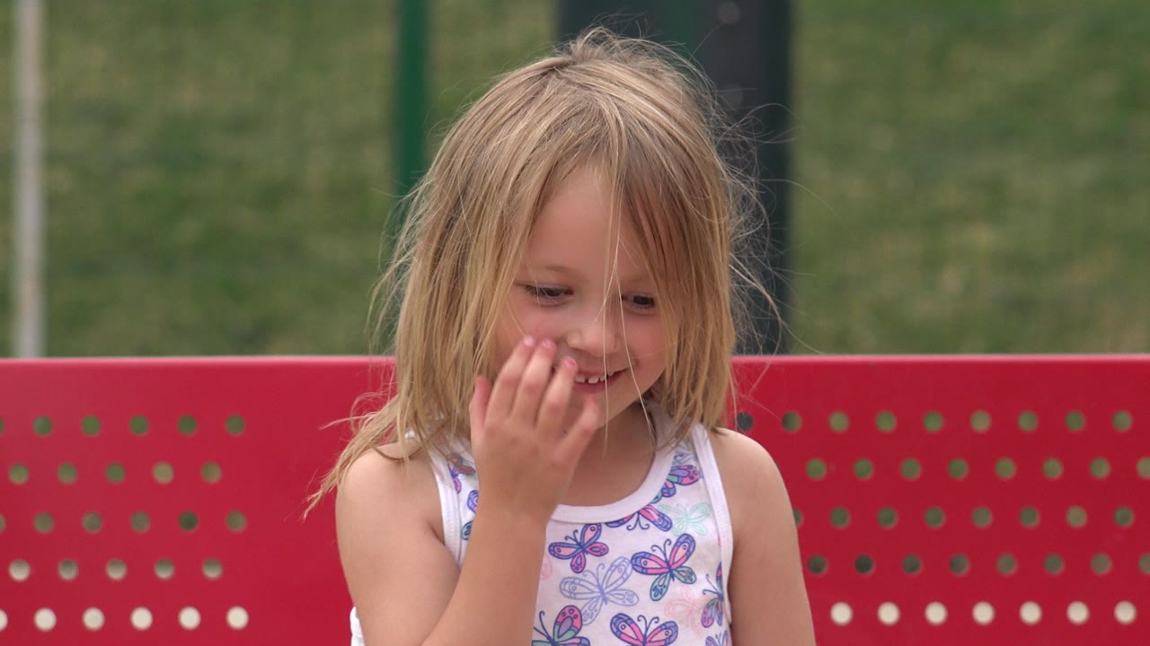 Young girl laughing with her hand near her mouth.