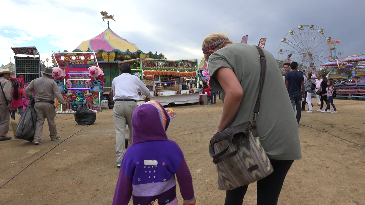 Child and adult walking toward colorful fair booths