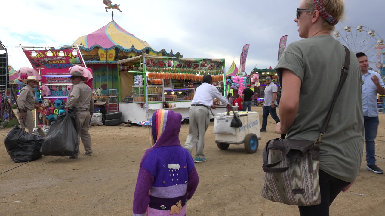 Mother and small child near colorful carnival booths.
