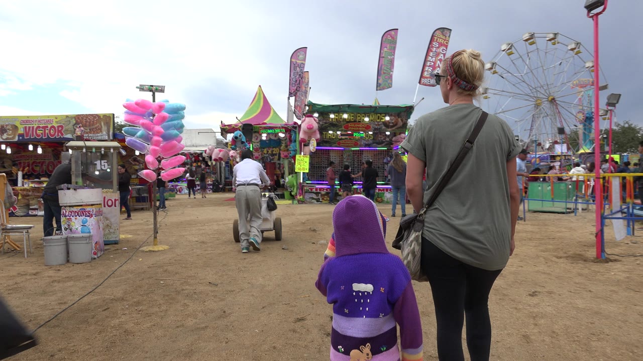 Woman and child walking toward carnival games and rides