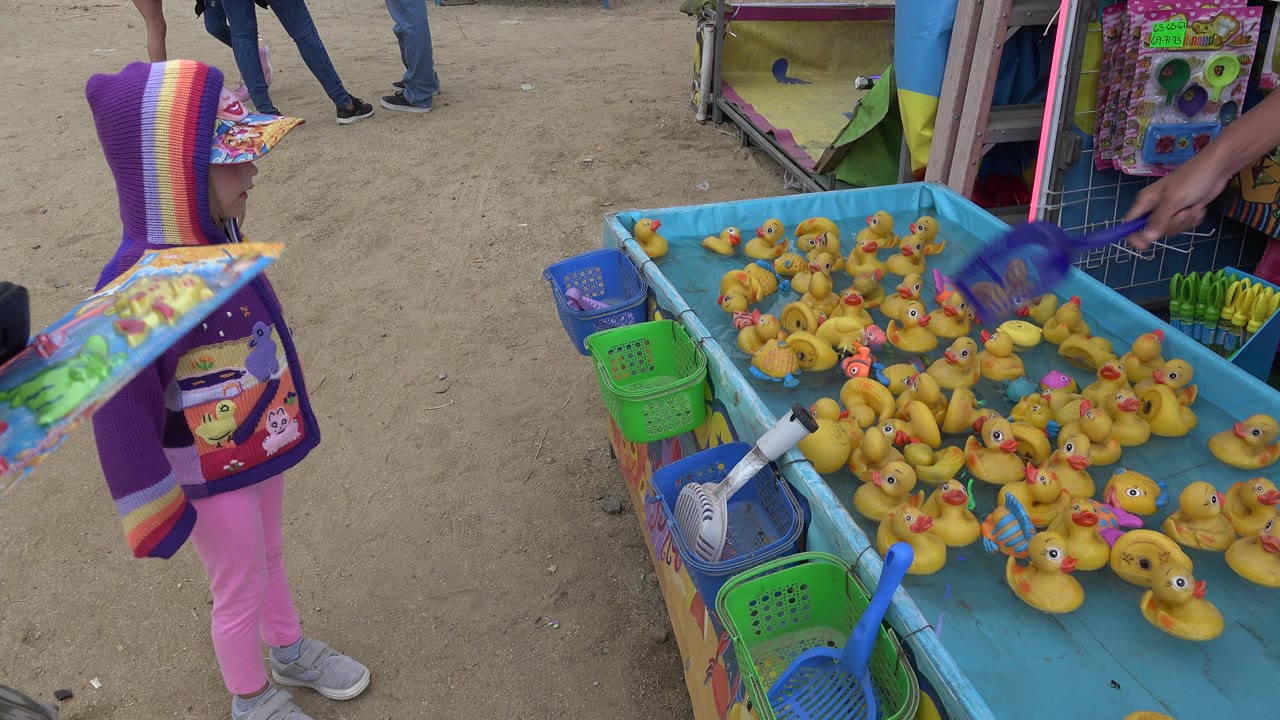 Young girl beside a blue duck pond carnival game.