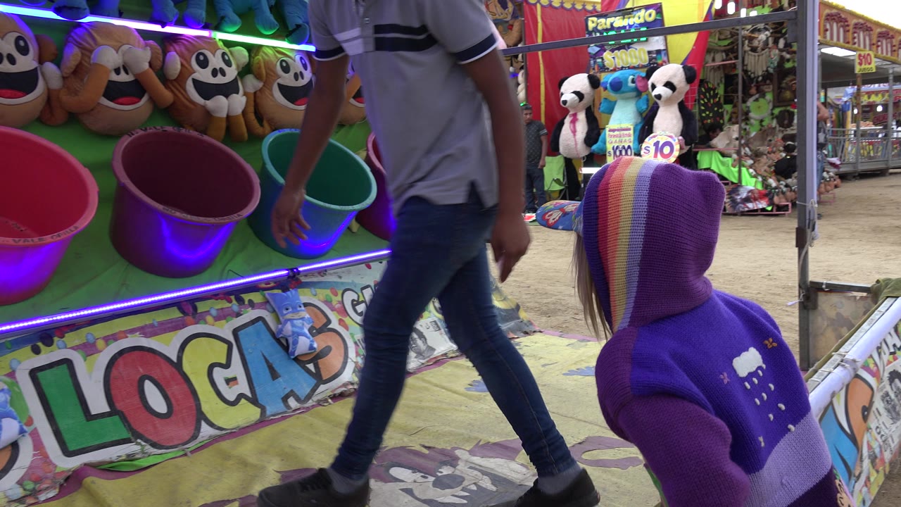 In San Jose del Cabo, Mexico, the attendant crosses in front of the bucket targets as the girl in the rainbow-striped hooded sweater watches from the foreground.