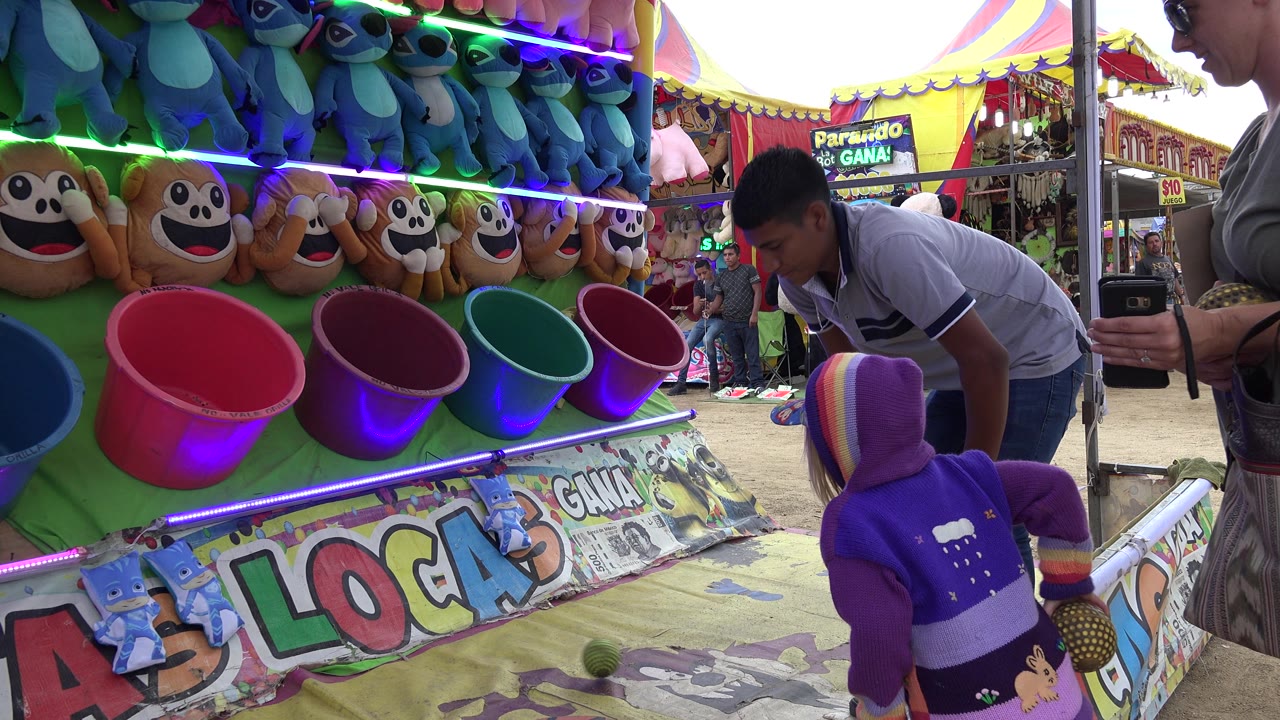 Game attendant bends toward the child at the ball toss booth.