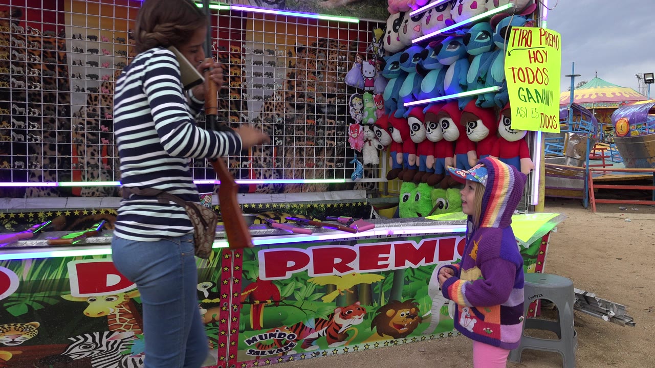 Attendant and small child at a carnival shooting booth.
