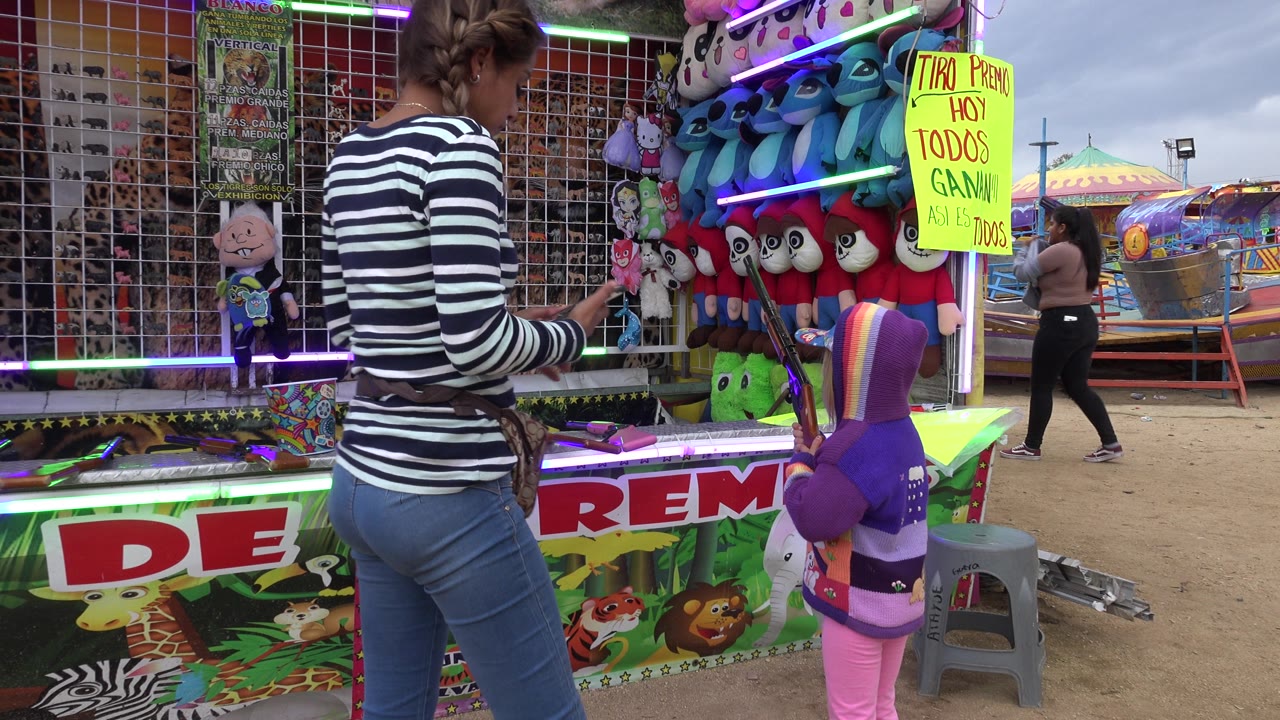 Woman reaches toward the carnival game as the child stands by the counter.
