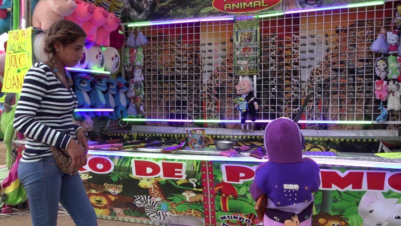 Woman steps past child at fair game booth.