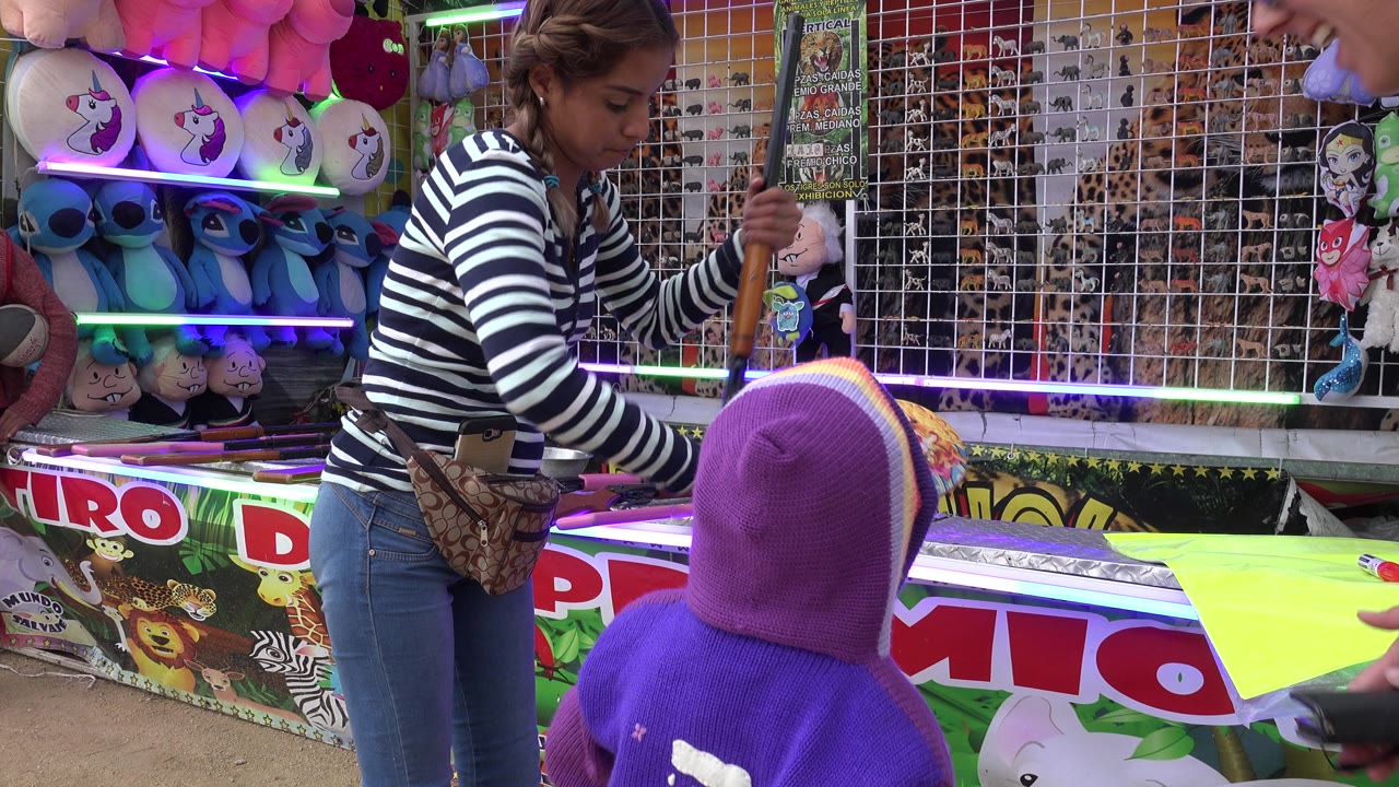 Game attendant reaches across the booth while a child faces the counter.