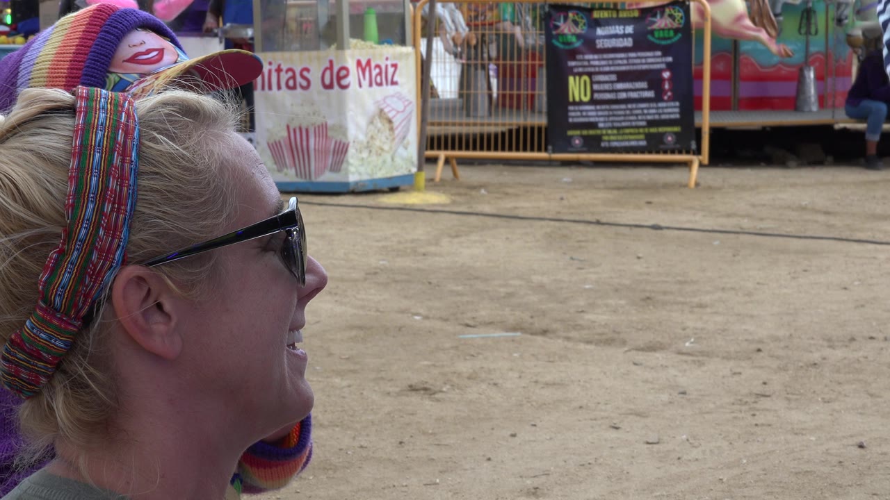 Woman in sunglasses seen in profile at a fairground booth.