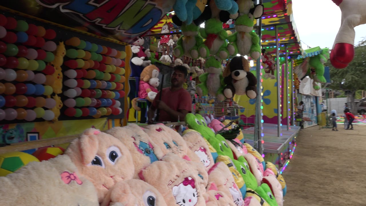 Carnival balloon booth with attendant and plush toys