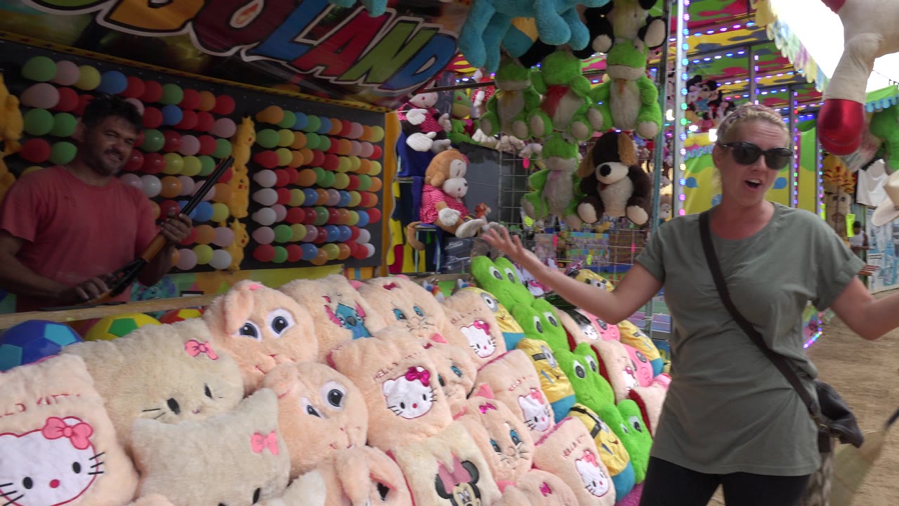 Woman beside plush prizes at a fair booth