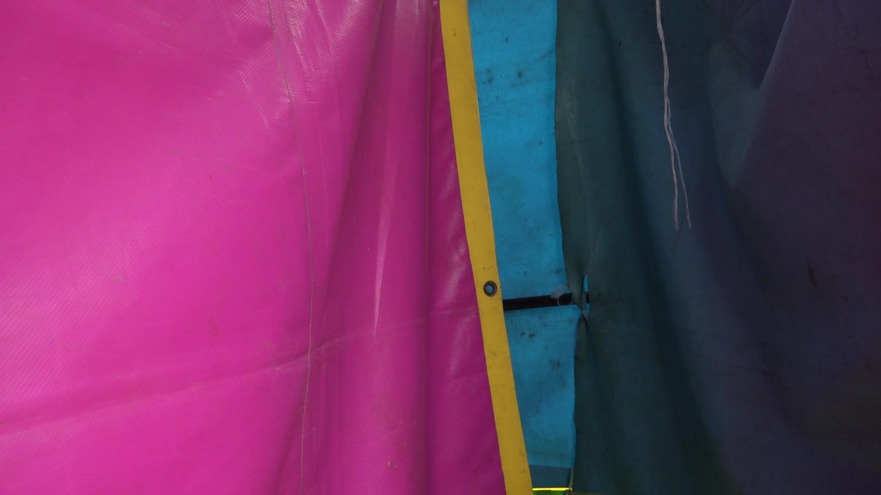 Close view of pink, yellow, blue, and dark tent fabric panels.