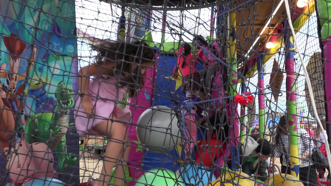 The girl shifts near the center of the netted bouncy house in San Jose del Cabo, Mexico, with a gray ball in front and other children partly visible behind the mesh.