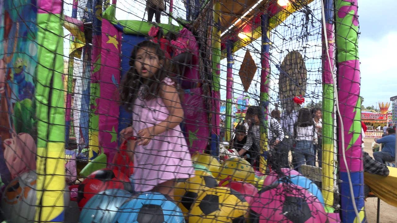 Girl in pink dress looks toward the camera inside the trampoline.