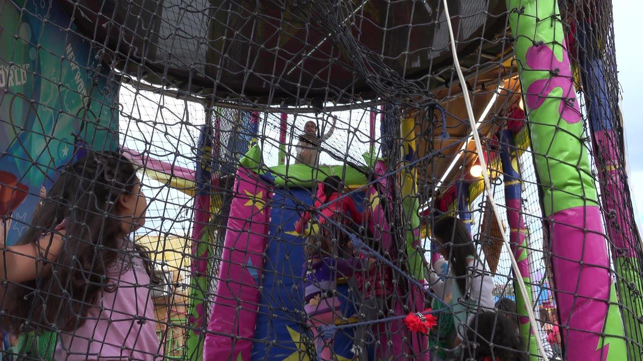 Children climb and play behind netting inside the bounce house.