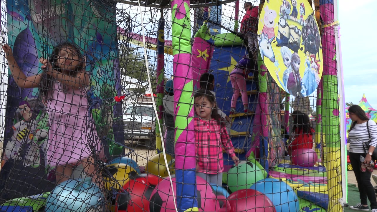 Children inside a colorful netted trampoline play area.